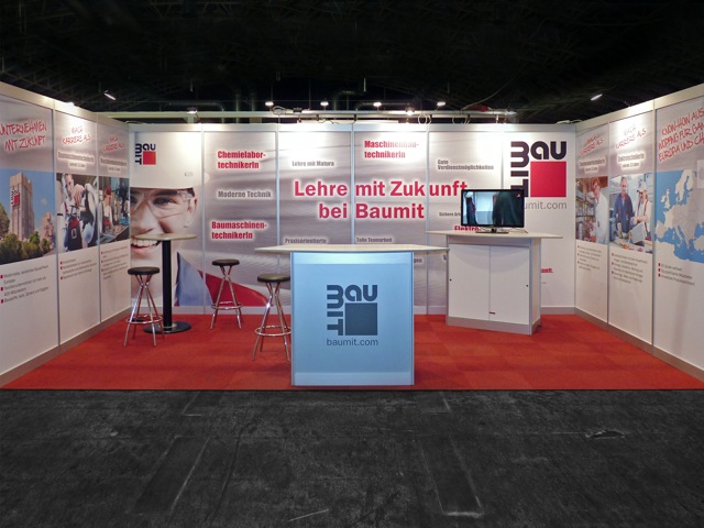 Realisierter Messestand mit roter Markenfläche und Besprechungsbereich